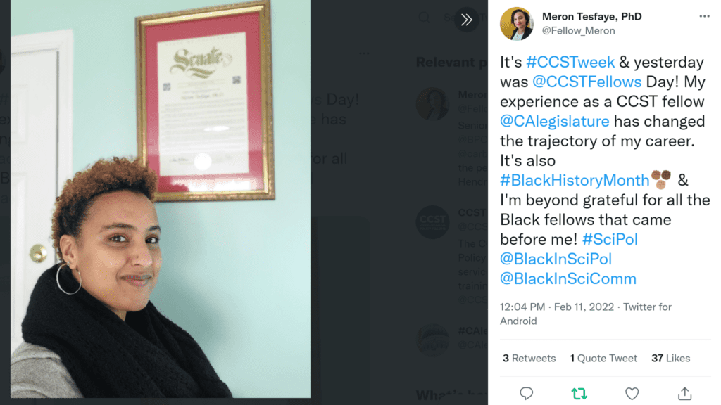 Screen shot of photo tweet by CCST Science & Technology Policy Fellow alum Meron Tesfaye PhD. She is seen with short hair, an ample scarf, and smiling in front of a California State Senate framed commendation on a wall. It's hashtag CCST week & yesterday was at CCSTFellows Day! My experience as a CCST fellow at CAlegislature has changed the trajectory of my career. It's also hashtag Black History Month   & I'm beyond grateful for all the Black fellows that came before me! hashtag SciPol at Black In Sci Pol at BlackInSciComm