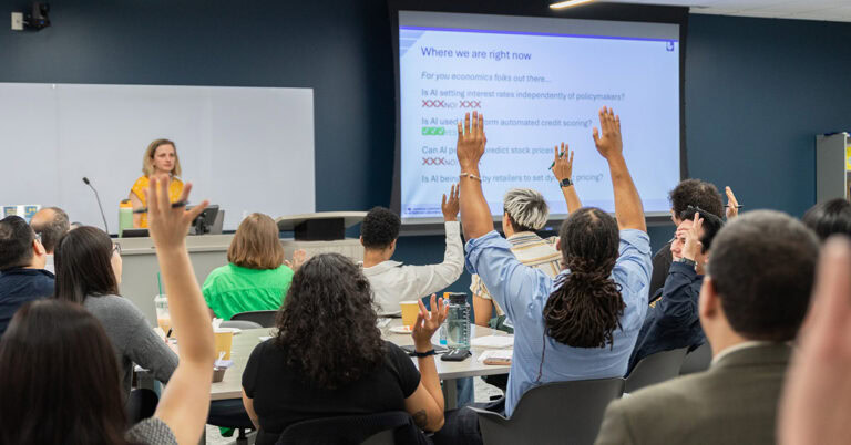 Attendees raise hands during a presentation at CCST's AI Academy for legislative staff.