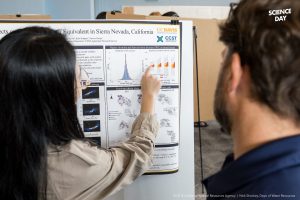 A poster presenter points to a chart on their poster