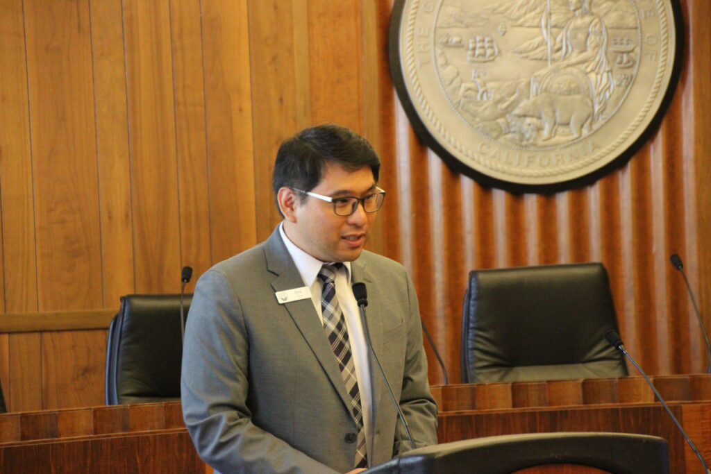 CCST Director of Science Eric Chu, PhD, speaking into a microphone in the Legislative Office Building.