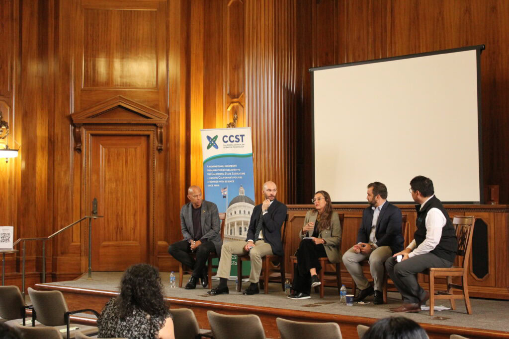 Four panelists on stage with moderator Eric Chu. In the center, panelist Soledad is speaking into a microphone as the other speakers turn to look at her.
