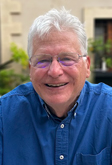 Headshot of Board member Jeff Scott in a blue button up shirt and wearing glasses.