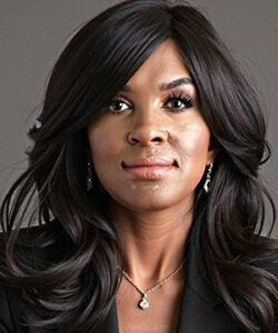 A headshot of Judith White in a black suit in front of a dark grey backdrop.