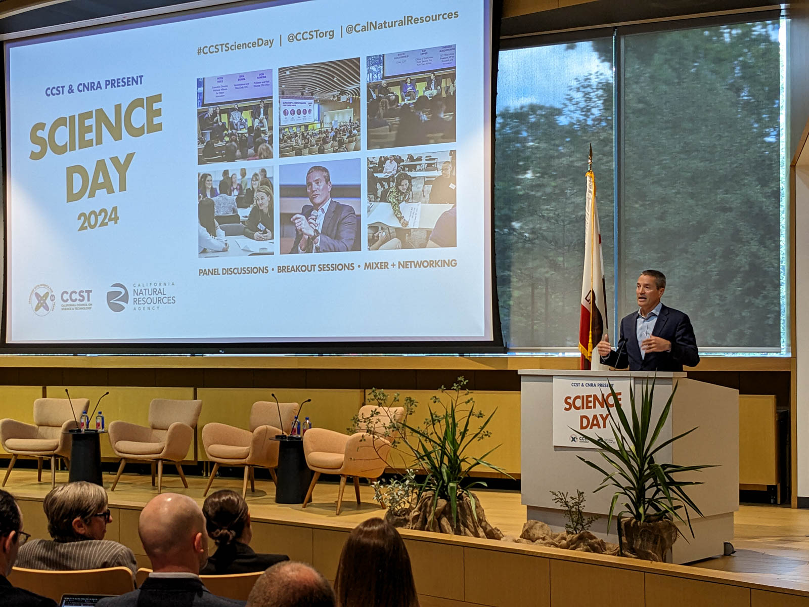 Secretary Crowfoot speaks at a podium with Science Day branding visible on a screen.