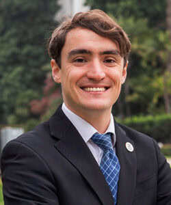 Professional headshot of Sean Clair in a suit in front of the California State Capitol Building.