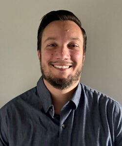 Headshot of Tyrel Long in a grey button down shirt.