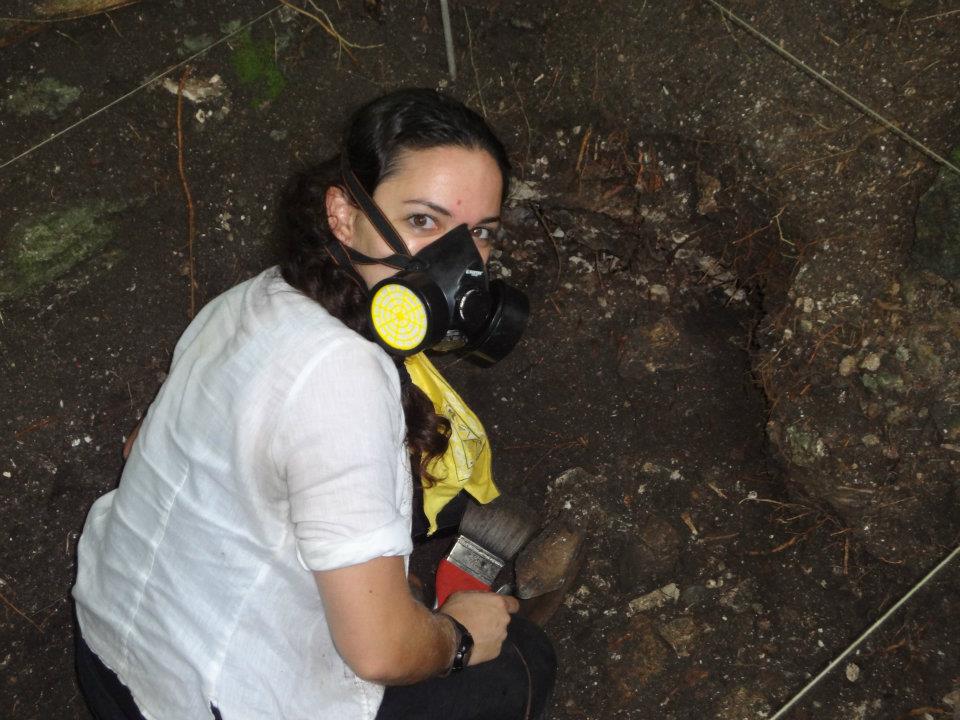 Bianca excavating an old Xultun (Maya underground storage) in the Belizean jungle, wearing a mask to protect from spores in the soil.