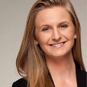 A headshot of Julianne McCall in business attire with a portrait crop and a light brown background.